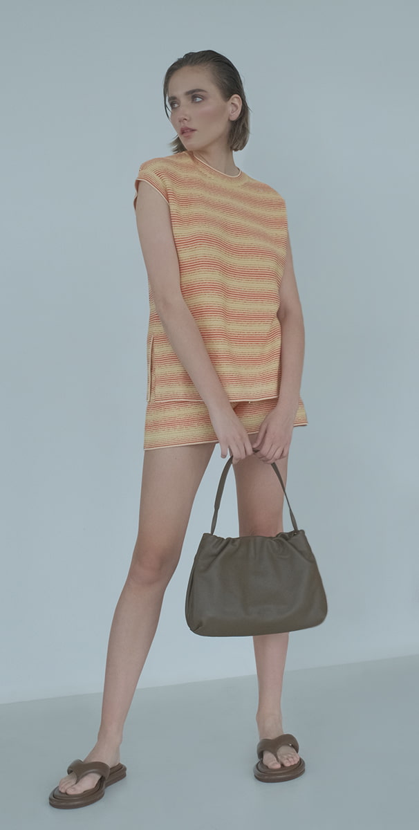 Woman wearing Loro Piana shirt , Bag The Row and Sandals-GIA